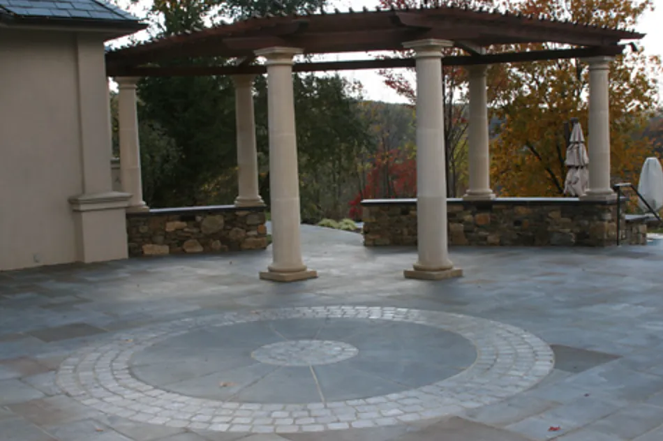 Bluestone terrace with a granite cobble compass medallion and fieldstone walls