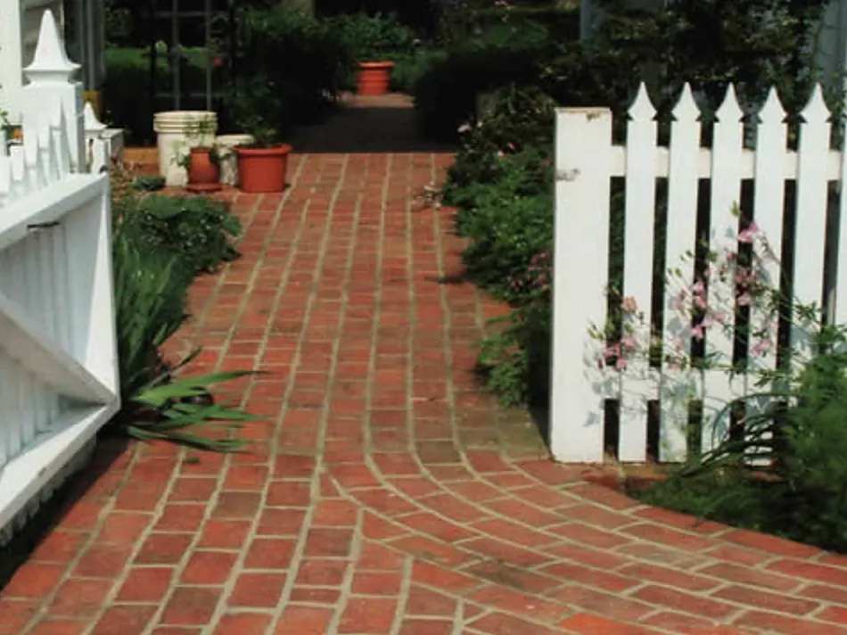 Running-bond brick garden path passing a white picket gate