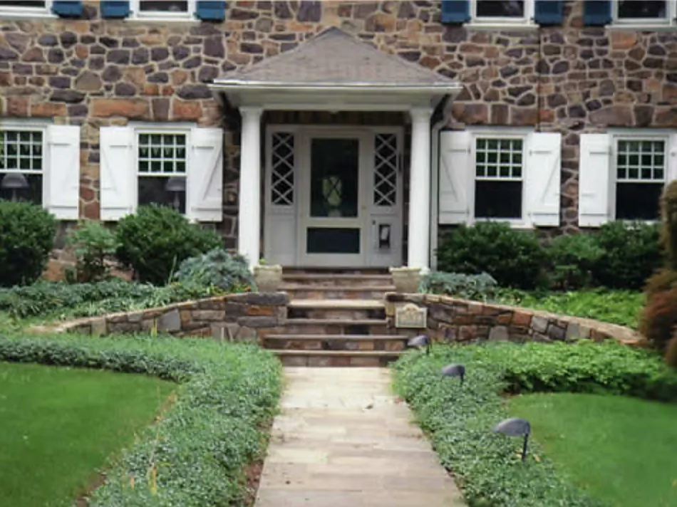 Flagstone front walk and steps framed by curved fieldstone planter walls