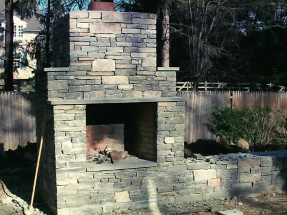 Stacked-stone outdoor fireplace with a bluestone hearth and mantel
