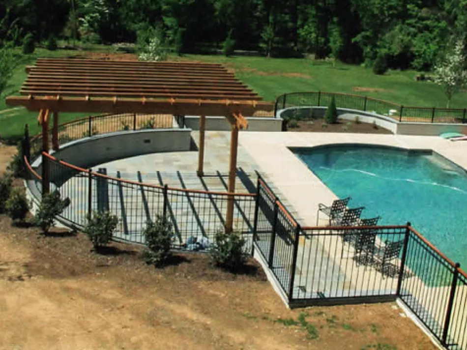 Curved retaining wall and bluestone pool terrace under a cedar pergola
