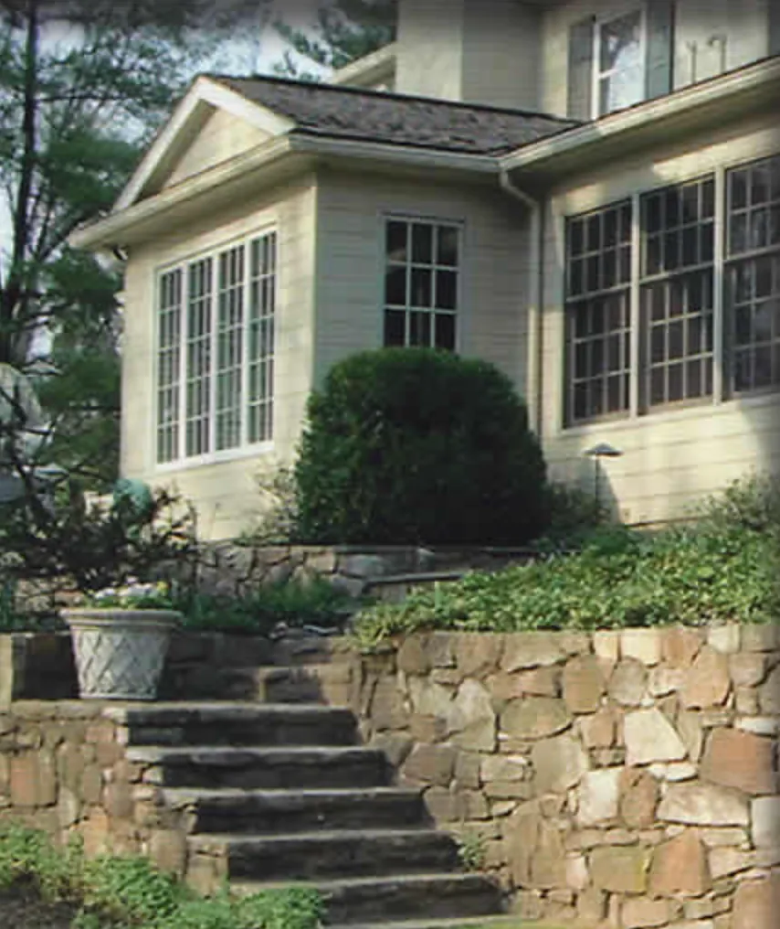 Stone steps set into a fieldstone retaining wall below a house